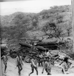 Foto di un passaggio dei guerriglieri eritrei acconto alle carcasse di carri armati nemici