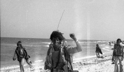 Foto di un operatore radio guerrigliero in marcia lungo il mare