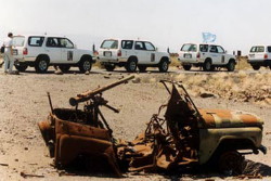 Foto: una fila di auto dei delegati ONU e una carcassa di auoto